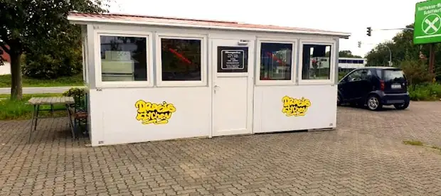 Der Imbisswagen von außen, mit Sitzplätzen und Parkplatz